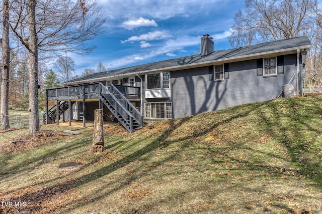 rear view of house featuring fence, stairway, a yard, a wooden deck, and a chimney