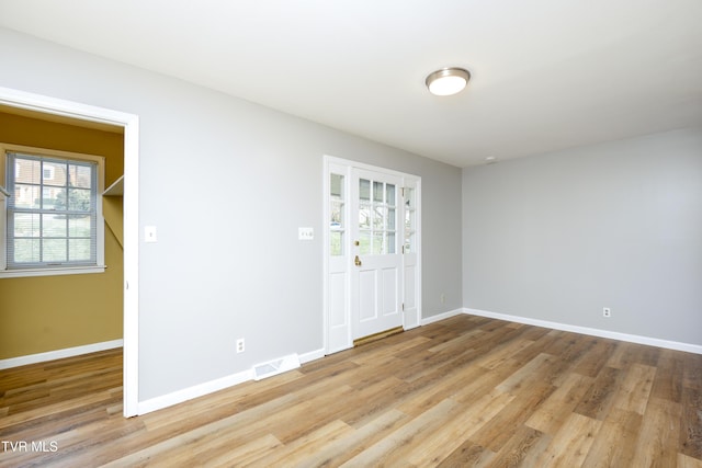 unfurnished room featuring visible vents, baseboards, and wood finished floors