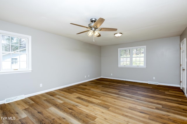 spare room with visible vents, a healthy amount of sunlight, ceiling fan, and wood finished floors