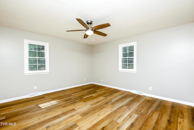 empty room featuring baseboards, wood finished floors, visible vents, and ceiling fan