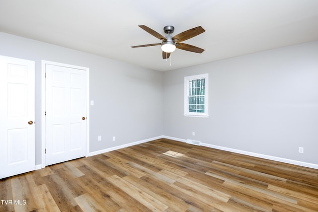 unfurnished bedroom featuring a ceiling fan, wood finished floors, visible vents, and baseboards