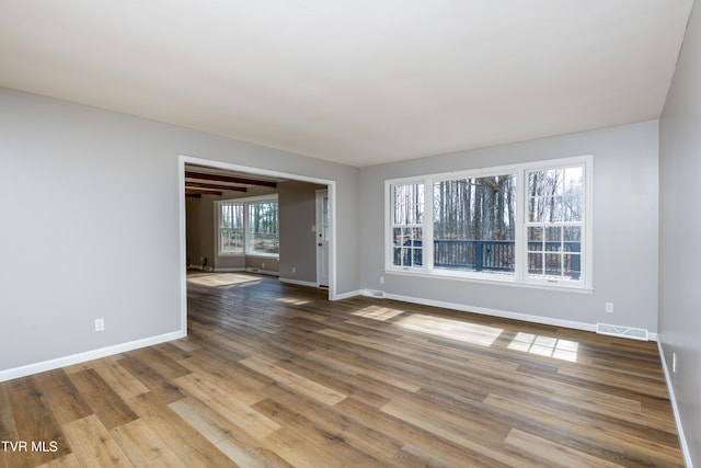 empty room with visible vents, baseboards, and wood finished floors