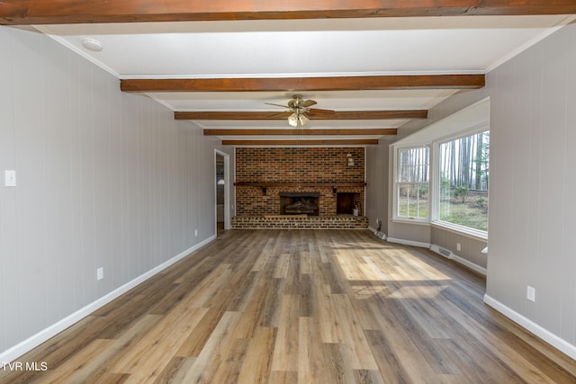 unfurnished living room with beam ceiling, wood finished floors, a fireplace, and ceiling fan