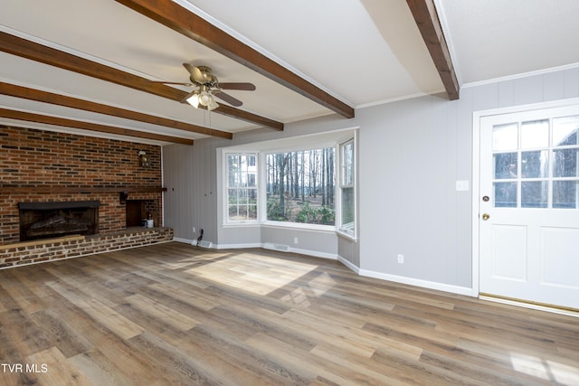 unfurnished living room featuring baseboards, beamed ceiling, a fireplace, wood finished floors, and a ceiling fan