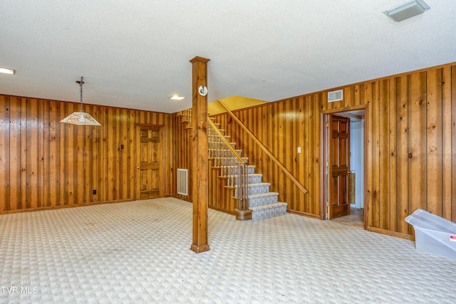 finished below grade area featuring stairway, wooden walls, carpet, and visible vents