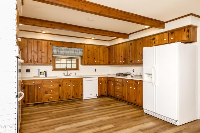 kitchen with a sink, beamed ceiling, white appliances, and brown cabinets