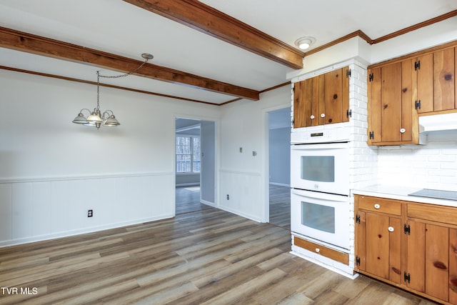 kitchen with brown cabinetry, beamed ceiling, light wood-style flooring, and double oven