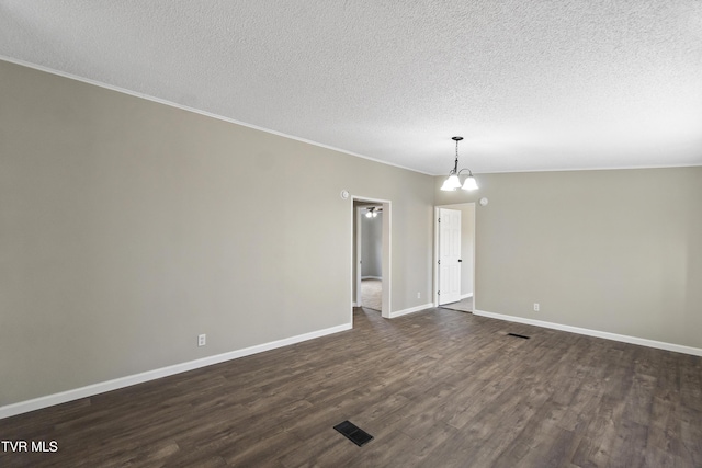 unfurnished room featuring baseboards, dark wood finished floors, ornamental molding, an inviting chandelier, and a textured ceiling