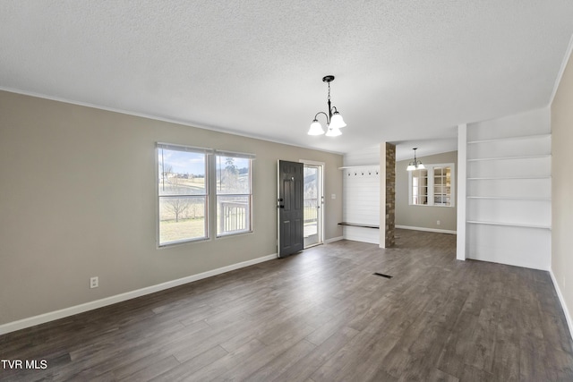 interior space with baseboards, a textured ceiling, an inviting chandelier, and dark wood-style flooring