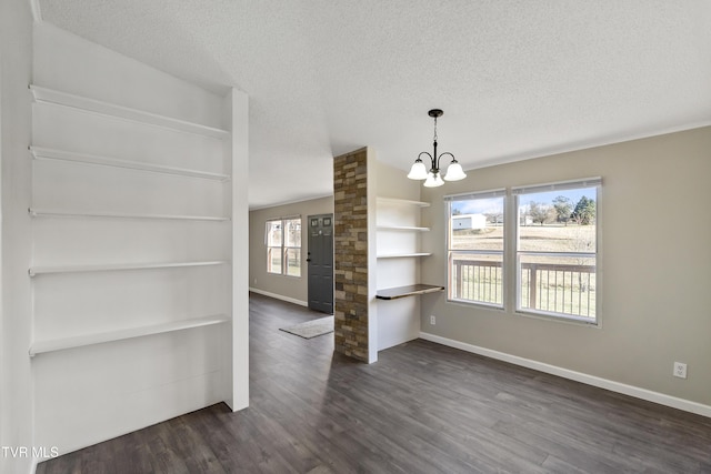 unfurnished dining area with an inviting chandelier, dark wood-style floors, baseboards, and a textured ceiling