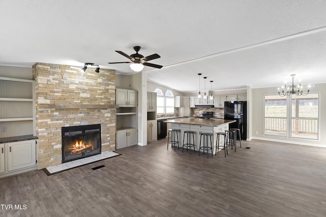 kitchen with a breakfast bar, a fireplace, black appliances, and dark wood-type flooring