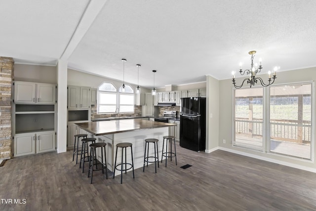 kitchen featuring a kitchen island, electric range, freestanding refrigerator, a sink, and a notable chandelier