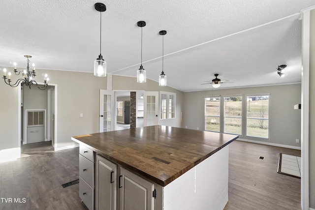 kitchen featuring dark wood finished floors, open floor plan, ceiling fan with notable chandelier, and wooden counters