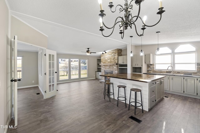 kitchen featuring a center island, lofted ceiling, ceiling fan with notable chandelier, a kitchen breakfast bar, and plenty of natural light