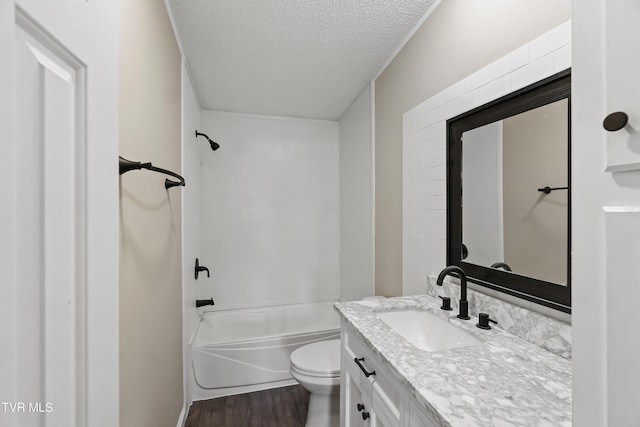 bathroom featuring toilet, a textured ceiling, wood finished floors, bathtub / shower combination, and vanity