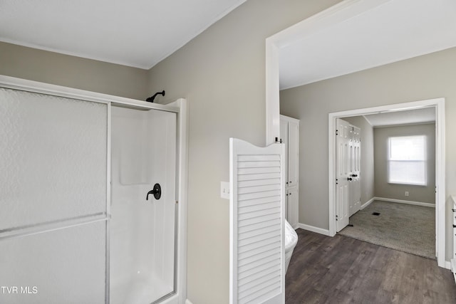 full bath featuring baseboards, wood finished floors, and a stall shower