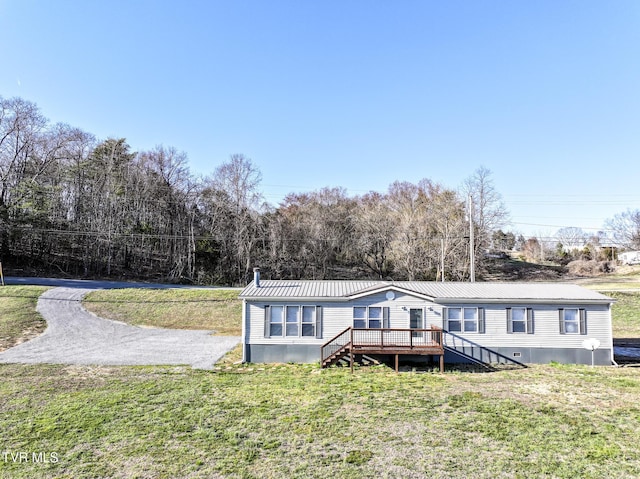 manufactured / mobile home with a wooden deck, metal roof, and a front lawn