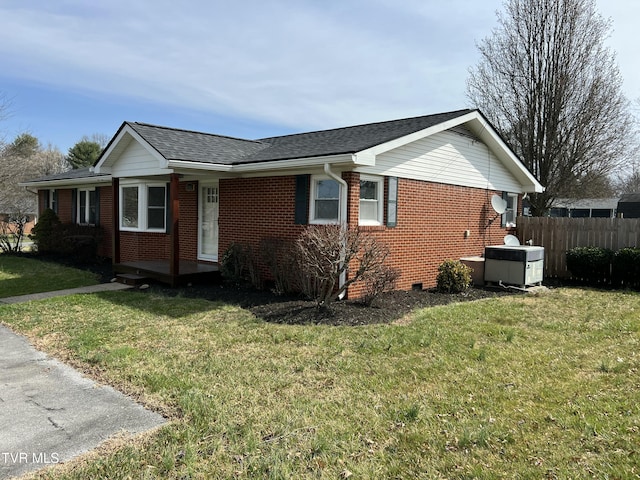 view of side of home featuring crawl space, brick siding, a lawn, and fence