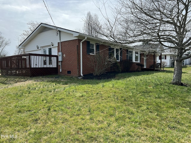 view of side of property with brick siding, a lawn, and a deck