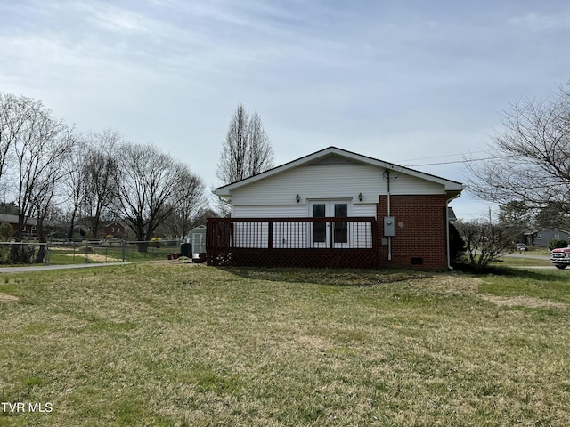 view of side of property featuring french doors, a lawn, brick siding, and fence