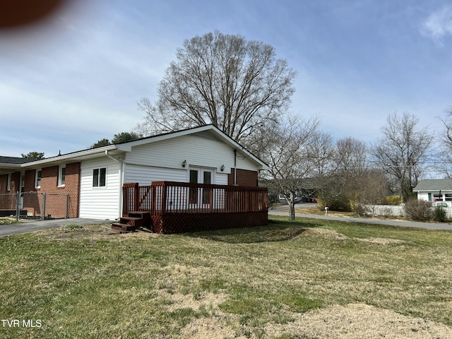 back of house with a lawn, a deck, and brick siding