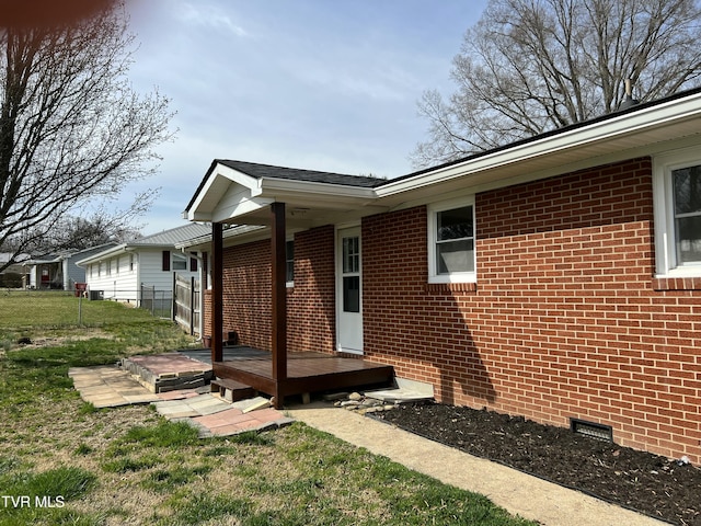 view of side of home featuring crawl space, a yard, brick siding, and fence