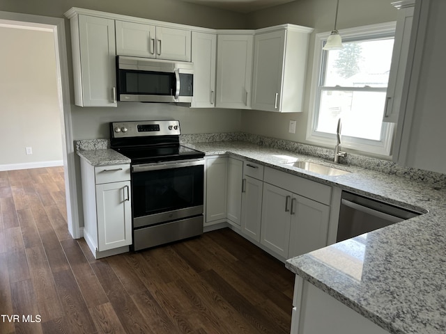 kitchen featuring light stone countertops, dark wood finished floors, a sink, stainless steel appliances, and white cabinetry