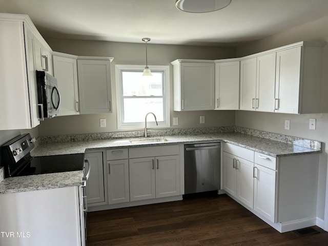 kitchen with light stone counters, stainless steel appliances, dark wood-style floors, white cabinetry, and a sink