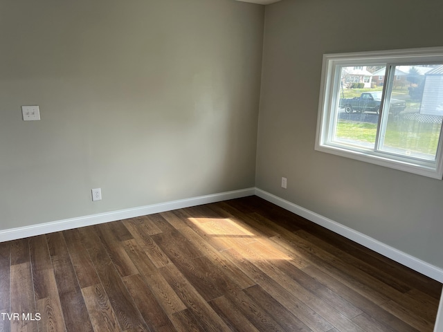 empty room featuring dark wood finished floors and baseboards