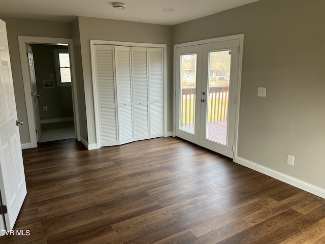 unfurnished bedroom featuring dark wood-style floors, baseboards, access to exterior, french doors, and a closet