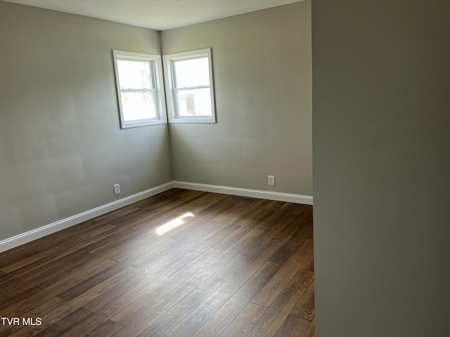 empty room with dark wood finished floors and baseboards