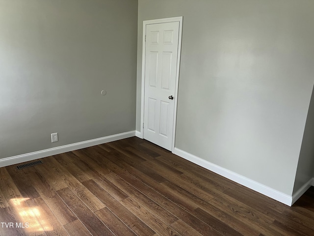 unfurnished room with dark wood finished floors, visible vents, and baseboards