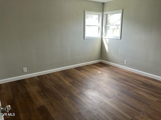 spare room with visible vents, dark wood-type flooring, and baseboards