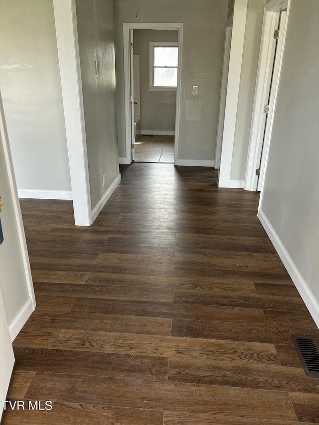 corridor with visible vents, baseboards, and dark wood finished floors