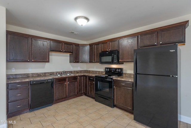 kitchen featuring visible vents, black appliances, a sink, dark countertops, and dark brown cabinetry