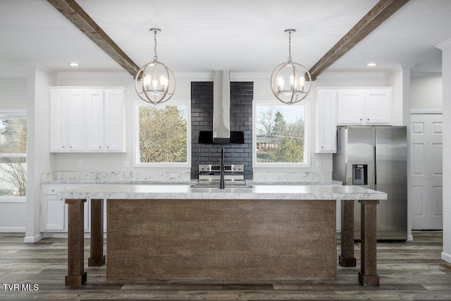 kitchen with beam ceiling, a notable chandelier, wall chimney exhaust hood, and stainless steel appliances