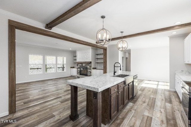 kitchen with beamed ceiling, a notable chandelier, a sink, light wood finished floors, and dark brown cabinets