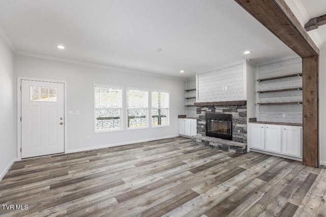 unfurnished living room featuring crown molding, wood finished floors, and a wealth of natural light