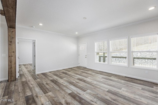 spare room with baseboards, wood finished floors, and crown molding