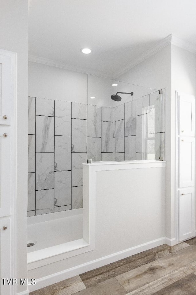 bathroom with baseboards, walk in shower, wood finished floors, and crown molding