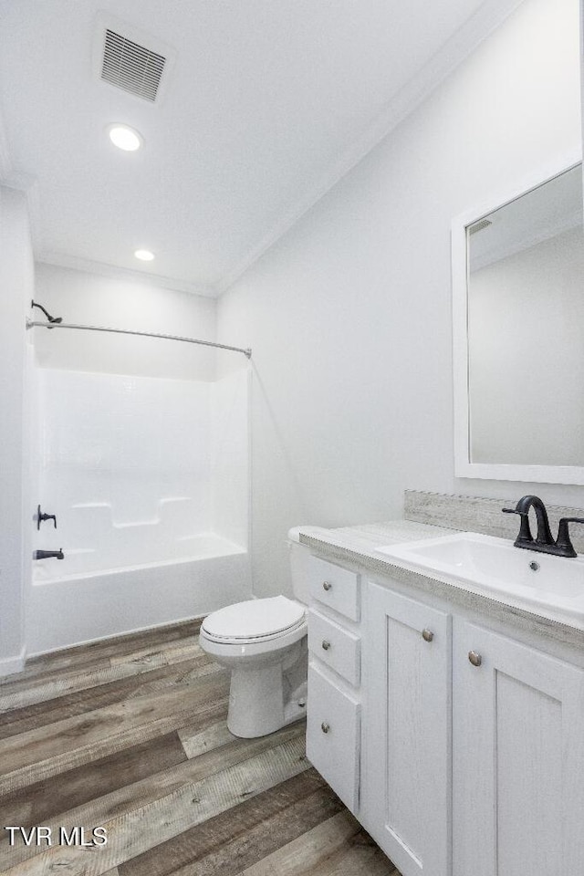 full bath with visible vents, toilet, wood finished floors, bathtub / shower combination, and vanity