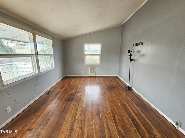 spare room featuring visible vents, ornamental molding, dark wood-type flooring, and vaulted ceiling