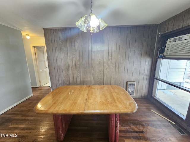 dining space featuring visible vents, a notable chandelier, wood finished floors, wooden walls, and baseboards