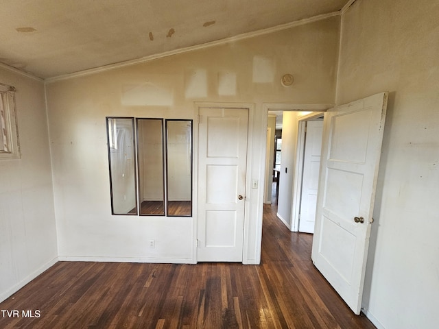 empty room with baseboards, wood finished floors, vaulted ceiling, and ornamental molding