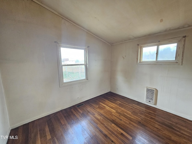 spare room with visible vents, heating unit, wood finished floors, baseboards, and vaulted ceiling