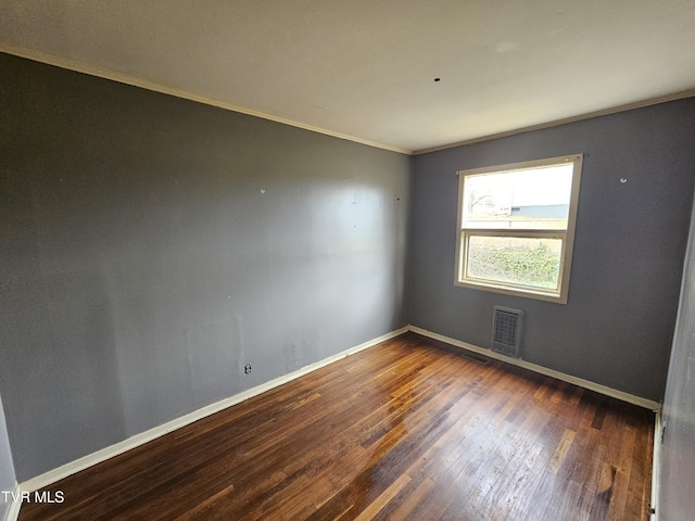 spare room with hardwood / wood-style floors, visible vents, baseboards, and ornamental molding