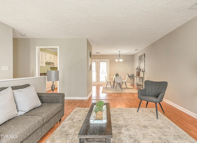 living area with baseboards, an inviting chandelier, and wood finished floors