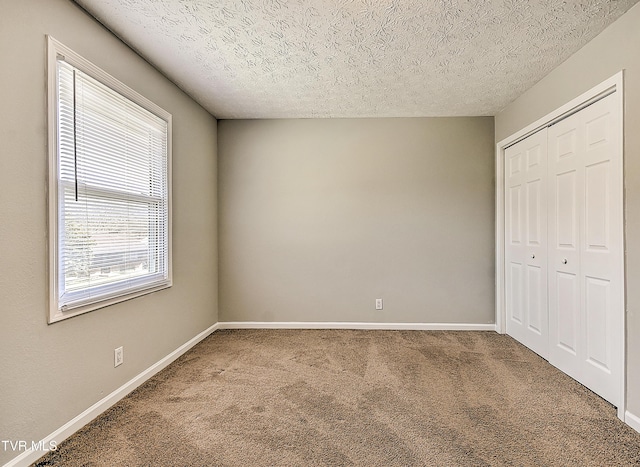 unfurnished bedroom with a closet, carpet flooring, a textured ceiling, and baseboards