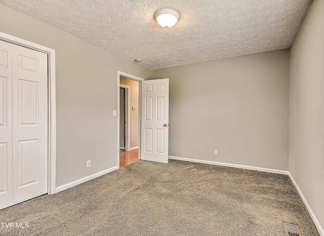 unfurnished bedroom with visible vents, baseboards, carpet, and a textured ceiling