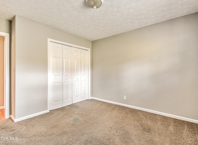 unfurnished bedroom with a closet, a textured ceiling, baseboards, and carpet
